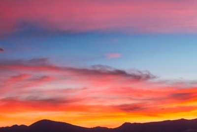 轮廓多云的蓝天下的山日落期间拍摄
